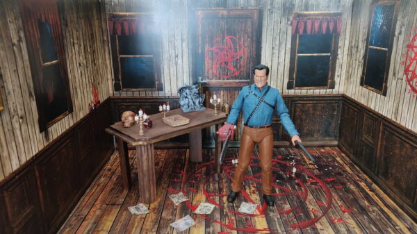 Diorama en 2D de la serie de Ash vs Evil Dead, con artículos que acompañan el diorama, como el Necronomicón, cráneo, candelabros, mesón, con frasco de pociones y figura de Ash totalmente nueva, marca Neca.